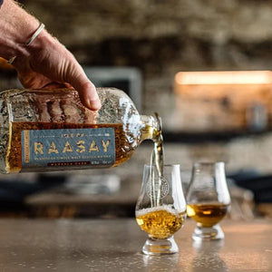 Pouring Raasay single malt Scotch whisky into Glencairn glass on a bar top