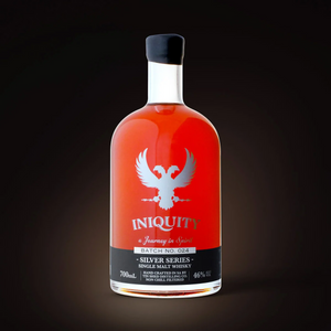 A bottle of Iniquity Silver Series Single Malt Whisky with a bright red liquid, a silver phoenix logo, and a black label, set against a dark background.