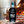 Bottle of Slyrs Malt Whisky with a glass on a wooden barrel against a blurred background